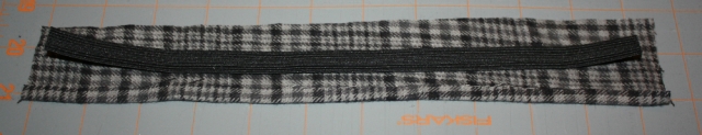 fabric cut for the neck band with the elastic laying in the center to show differences in length.